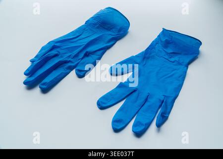 Ein Paar blaue medizinische Nitril-Handschuhe liegen flach auf einem sauberen weißen Hintergrund. Stockfoto