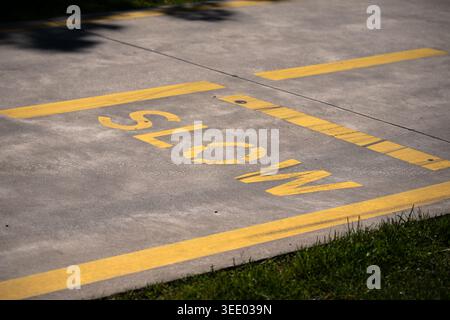 Hochwinkelaufnahme des Wortes LANGSAM in Gelb auf einem grauen Betonweg mit Grasrand Stockfoto