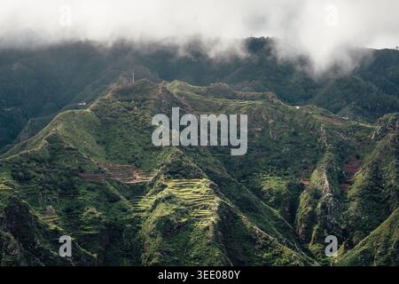 Steile Berge, die unter dem bewölkten Himmel auf Teneriffa auf den Kanarischen Inseln sanft beleuchtet werden Stockfoto
