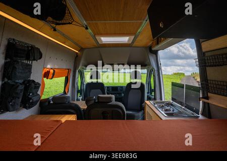 Weitwinkelansicht eines professionellen Wohnmobils, der Innenraum mit Bett, Küche und Kabinensitzen umgebaut wurde. Wunderschönes Holzdesign mit Blick auf Green Falling Stockfoto