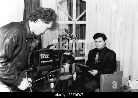 Sloviansk, 1997, Sloviansk Television. Dieses fesselnde Schwarzweiß-Archivfoto zeigt einen Kameramann, der eine große Panasonic-Videokamera verwendet, um einen männlichen Nachrichtenanker zu filmen, der aus einem Skript auf einem einfachen Studioset liest. Dieses authentische historische Dokumentarfilm bewahrt die einzigartige professionelle Atmosphäre der postsowjetischen Ära und zeigt regionale Nachrichtensendungen, Vintage-TV-Produktionsausrüstung, tägliche Medienabläufe und die äußerst wichtige historische Essenz eines friedlichen Donbas. Stockfoto