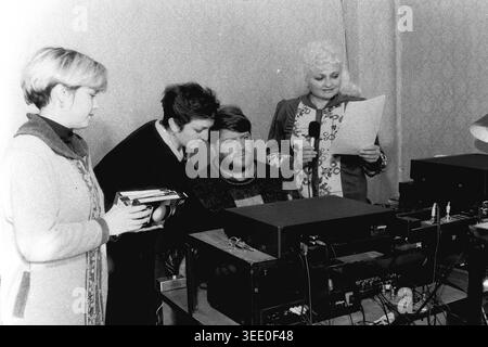 Sloviansk, 1997, Sloviansk Television. Dieses interessante Schwarzweiß-Archivfoto zeigt ein kreatives Team von Frauen und einem Mann, der in einem Studio-Kontrollraum arbeitet, in dem eine Dame ein Mikrofon hält, um VoiceOver-Audio aufzunehmen. Dieses authentische historische Dokumentarfilm bewahrt die einzigartige professionelle Atmosphäre der postsowjetischen Ära und zeigt regionale Medienübertragungen, Vintage-TV-Produktionsausrüstung, tägliche Teamarbeit und die hochwichtige historische Essenz eines friedlichen Donbass. Stockfoto