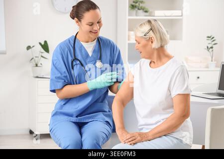 Ärztin impfende Seniorin in der Klinik Stockfoto
