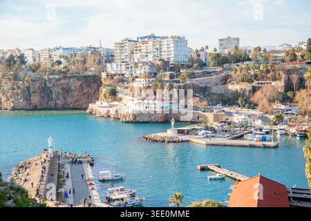 Türkisfarbene Bucht des alten Hafens von Kaleici, flankiert von Kalksteinklippen und Yachthafen mit Booten, Stadtgebäuden und Palmen auf der Spitze. Antalya, Türkei. Stockfoto