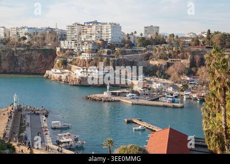 Panoramablick auf den römischen Hafen von Antalya mit Leuchtturm, felsigen Klippen, verankerten Booten und Wohngebäuden. Kaleici Altstadt, Antalya, Türkei. Stockfoto