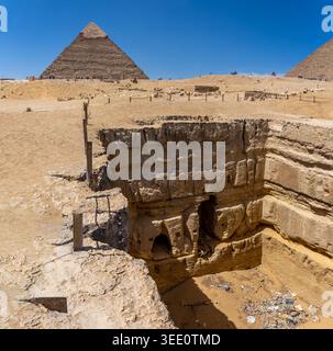 Blick auf einen riesigen Schacht, einer von vielen, die auf dem Gizeh-Plateau zu sehen sind. Im Hintergrund die Pyramide von Khafre. Stockfoto