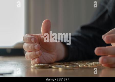 Großaufnahme von Kinderhänden, die Münzen auf Holztisch in natürlichem Licht zählen. Finanzkompetenz und Sparkonzept, das sich auf das Lehren von Geldmana für Kinder konzentriert Stockfoto