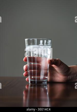Nahaufnahme einer Hand, die große Eiswasser zum Trinken hält. Stockfoto