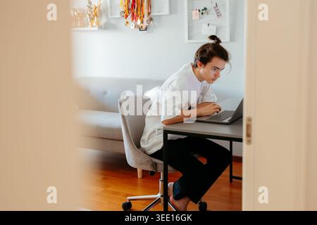 Fokussierte junge Person, die zu Hause am Laptop arbeitet Stockfoto