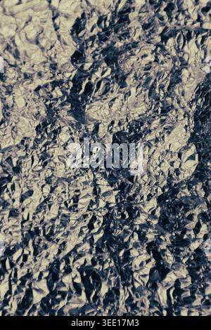 Silberne zerknitterte Aluminiumfolie, flache Hintergrundstruktur. Glänzende Metallsilbergraue Folie zerknitterte Textur Hintergrund. Abstrakter Hintergrund der zerknitterten Folie Stockfoto