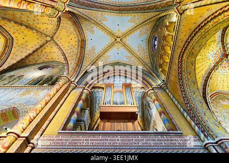Besucher blicken auf die detailreiche Decke und Orgel der Matthiaskirche im Budaer Schloss, Budapest, und genießen die historische Architektur und Kunstfertigkeit. Stockfoto
