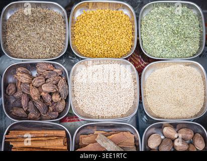 Verschiedene Gewürze, Gewürze in den Metallplatten. Auswahl an Gewürzen und Samen, Draufsicht. Kreuzkümmel, Kardamom, Sesamsamen, muskatnuss, Fenchel, m Stockfoto