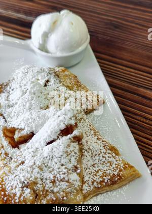 Strudel aus Hefefreiem Blätterteig mit Äpfeln, mit Puderzucker und einer Eiskugel bestreut. Süßes Dessert für Kaffee oder Tee. A Stockfoto