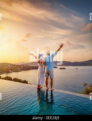 Ein glückliches Paar im Sommerurlaub am Swimmingpool genießt einen wunderschönen Sonnenuntergang hinter dem Meer Stockfoto