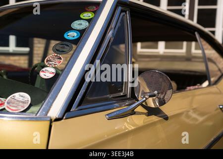BERLIN, DEUTSCHLAND - 2. MAI 2026. Nahaufnahme eines klassischen Chevrolet Coupés mit verchromtem Seitenspiegel, Aufklebern an der Windschutzscheibe und goldener Karosserie im Oldtimer Stockfoto