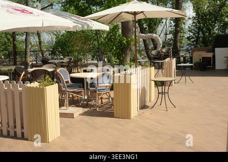 Helles und einladendes Café mit gemütlichen Stühlen, Sonnenschirmen und Grün. Andriyivskyy Descent, Kiew, Ukraine, 8. Mai 2026 Stockfoto