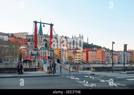 Lyon, Frankreich - 19. März 2026: Die berühmte rote Passerelle Saint-Georges-Brücke über den Saone-Fluss mit farbenfrohen Gebäuden und dem Fourviere-Hügel Stockfoto