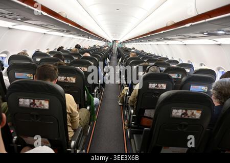 Blick auf den Gang des Flugzeugs im Flug mit Passagieren im Sitzen Stockfoto