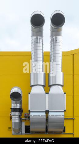 Abstrakte Nahaufnahme industrieller Metalllüftungsrohre auf hellgelbem Hintergrund Stockfoto
