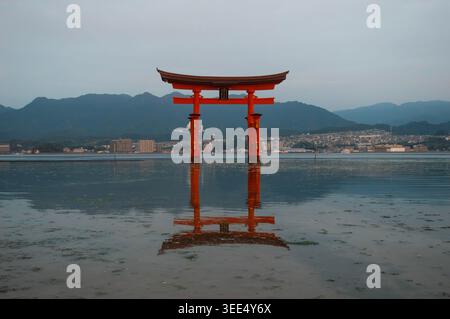 Miyajima, Japan – der Itsukushima-Schrein spiegelt sich in ruhigem Wasser bei Flut unter einem bewölkten Morgenhimmel. Stockfoto