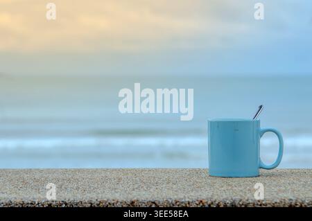 Blauer Becher am Strand mit blauem Meer und Himmel Stockfoto