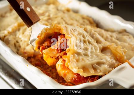 Ein Blick auf einen Spachtel, der ein Stück glutenfreier, milchfreier Lasagne hochhebt. Stockfoto
