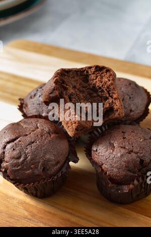 Ein Blick auf einige milchfreie, glutenfreie Schokoladen-Muffins, darunter einer mit einer Bissspur. Stockfoto