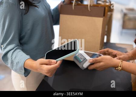 Nahaufnahme einer Frau, die ihr Smartphone benutzt, um kontaktlos zu bezahlen Stockfoto