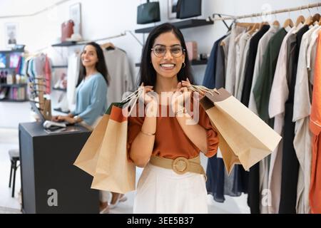 Glückliche Frau, die Einkaufstaschen in der Boutique hält Stockfoto
