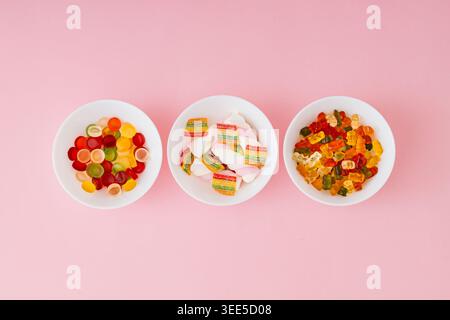 Kreative Komposition aus gummiartigen Bonbons auf pastellrosa Hintergrund. Minimales trendiges Gummikonzept. Gelee-Süßigkeiten-Ästhetik. Farbenfrohe flache Lagen. Stockfoto