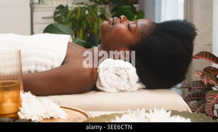 Entspannte Frau, Die Eine Spa-Behandlung Erhält, Liegend Auf Einem Massagetisch Mit Handtuch Im Ruhigen Zimmer Stockfoto