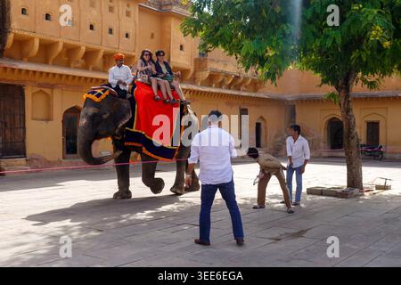 Touristen, die auf einem dekorierten Elefanten durch den historischen Innenhof von Amber Fort in Jaipur, Indien, reiten Stockfoto