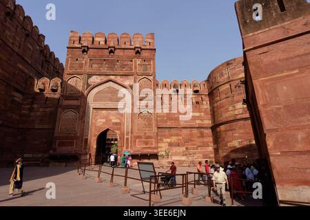 Touristen betreten die historischen roten Sandsteinmauern des Agra Fort, das zum UNESCO-Weltkulturerbe in Indien gehört Stockfoto