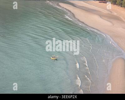Aus der Vogelperspektive mit Blick auf den ruhigen Strand mit ruhigem Meereswasser und einem kleinen Boot, das nahe der Sandküste schwimmt, schaffen eine friedliche, ruhige Atmosphäre zum Entspannen Stockfoto