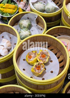 Verschiedene traditionelle chinesische Dim Sum in Bambus-Dampfkörben mit köstlichen Schweineknödeln und Gemüsebrötchen, die ein appetitliches Gefühl vermitteln Stockfoto