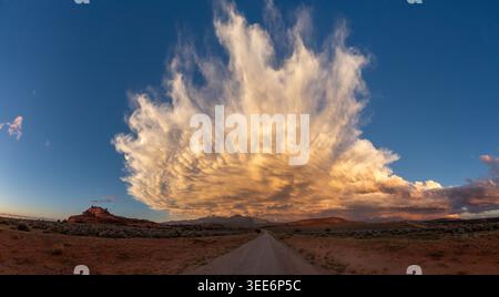 Blick auf eine unbefestigte Straße, die zu einer gewaltigen, dramatischen Wolkenbildung über der Wüstenlandschaft bei Sonnenuntergang führt, Utah, USA. Stockfoto