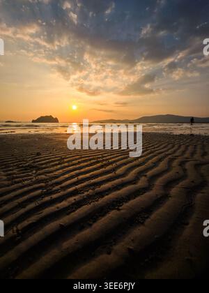 Friedliche Strandlandschaft bei Sonnenuntergang mit ruhiger Sandstruktur in der Nähe von ruhigem Meereswasser unter schönem goldenen Himmel und sehr ruhig Stockfoto