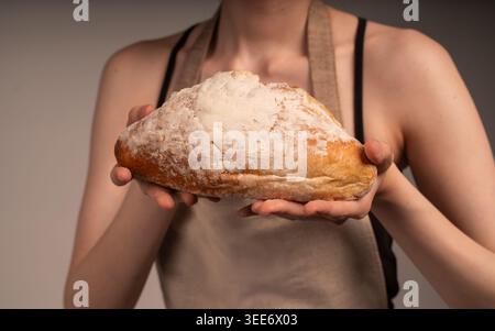 Baker hält frisches hausgemachtes, rustikales Sauerteigbrot mit einer mehlstaubten Kruste und präsentiert Backhandwerkskunst Stockfoto
