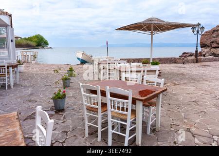 Traditionelle griechische Taverne mit weißen Holzstühlen und Tischen auf der Steinterrasse mit Blick auf die Ägäis im Dorf Skala Sikamineas auf der Insel Lesbos Stockfoto