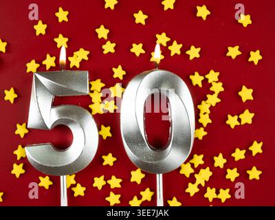 Konzept der Geburtstagsfeier und Jubiläumsfeier. Nummer 50 50 silberne Geburtstagskerze auf festlichem rotem Hintergrund. Fünfzig Jahre Geburtstag. F Stockfoto