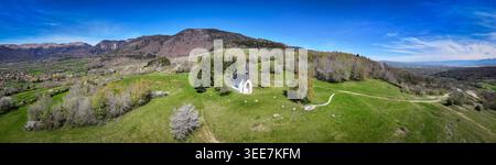 Luftaufnahme der Chapelle Notre-Dame de Riantmont auf einem grünen Hügel mit Bergen im Hintergrund in Vesancy, Auvergne-Rhone-Alpes, Frankreich. Stockfoto