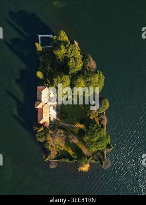 Blick aus der Vogelperspektive auf die kleine private Insel San Paolo am Iseo-See mit ihrer historischen Villa, üppigen grünen Gärten und hohen Zypressen, die lange SHA bilden Stockfoto