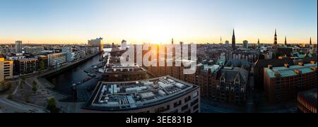 Blick aus der Vogelperspektive auf die Speicherstadt und die Elbphilharmonie bei Sonnenuntergang mit der Skyline der Stadt und Kirchtürmen in Hamburg, Ham Stockfoto