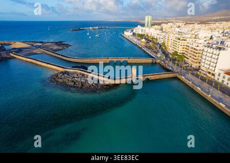 Aus der Vogelperspektive zeigt Lanzarote Küste mit Gebäuden entlang der Küste und Booten im Wasser. Die Szene fängt das urbane Gebiet von Arrecife unter Clear ein Stockfoto