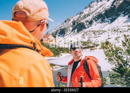 Glückliche Gruppe Trekker Freunde Wandern in der Nähe des verschneiten Zelene Pleso See hohe Tatra Slowakei mit Berghütte im Hintergrund als Konzept Wintertourismus aktiv Stockfoto
