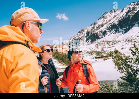 Glückliche Gruppe Trekker Freunde Wandern in der Nähe des verschneiten Zelene Pleso See hohe Tatra Slowakei mit Berghütte im Hintergrund als Konzept Wintertourismus aktiv Stockfoto