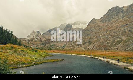 Refuge Elisabetta, Italien - 13.09.2025: Ein sich windender Fluss fließt durch ein goldenes Herbsttal in Richtung zerklüfteter Gipfel. Stockfoto