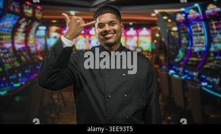 Hispanische Küchenchefin macht Friedenszeichen mit Hand und Fingern in einem Kasino-Gebäude; Selbstvertrauen-Feier. Stockfoto