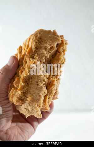 Ein Blick auf eine Hand, die ein Eis-Sandwich mit Erdnussbutter-Keksen hält. Stockfoto