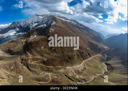 Blick aus der Vogelperspektive auf den Ratti Gali See umgeben von schneebedeckten Gipfeln, gewundenen Bergstraßen und einer kleinen Siedlung im Tal Neelum, Azad Kaschmir, Pak Stockfoto
